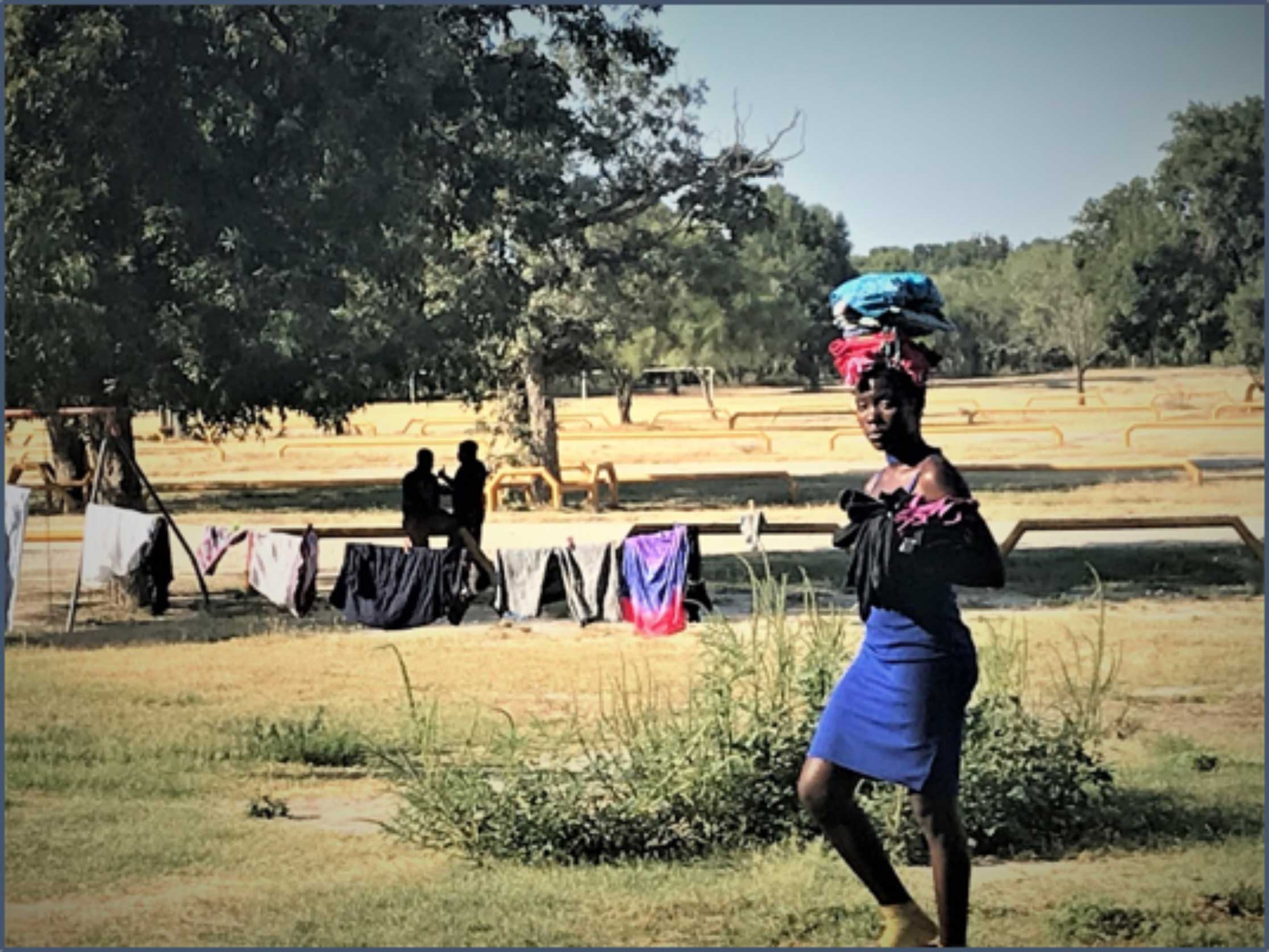 African migrant woman in Mexico drying laundry on the banks of the Rio Grande.