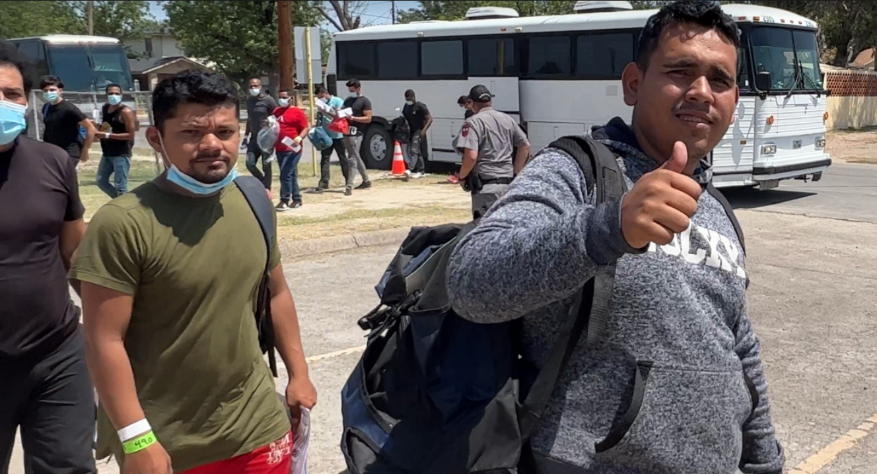 Border-crossers released from a white Border Patrol bus coming from a brief processing detention in Del Rio